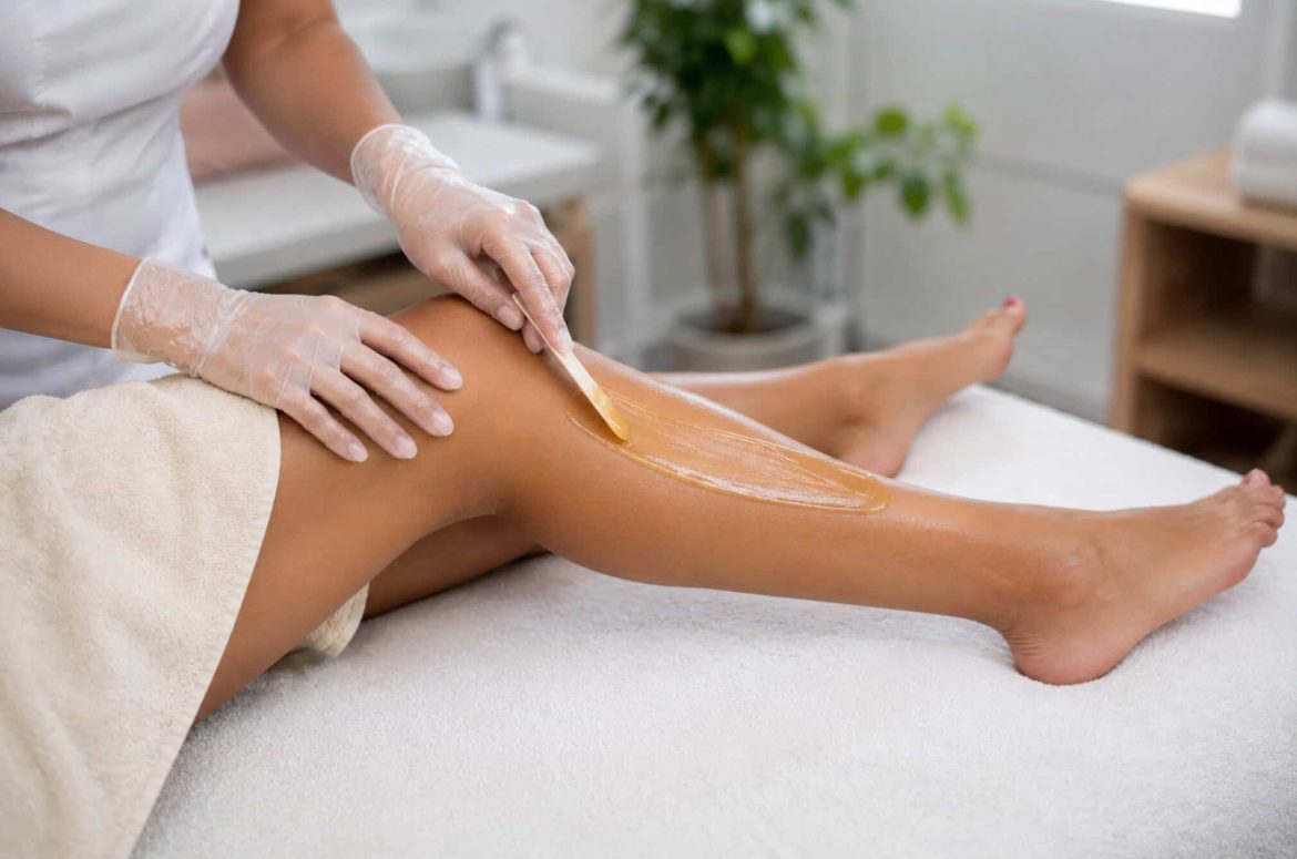 Gros plan sur l'application de cire chaude sur une jambe pour une épilation en institut de beauté.
